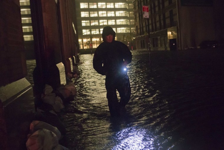 A security guard walks through a flooded street in the financial district of Manhattan, New York, on Oct. 30, 2012.