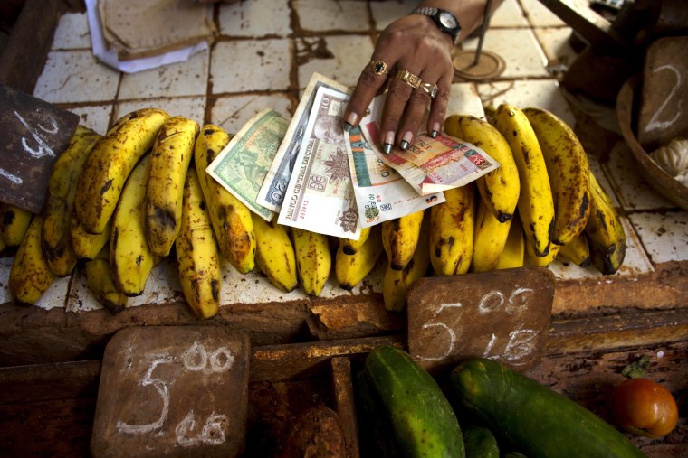 In this Aug. 30 file photo, a food vendor spreads out convertible pesos, known as CUCs - the two bills on the right - and regular Cuban pesos at her stand in a vegetable market in Havana, Cuba.