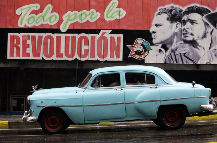 A U.S.-made car, used as a private collective taxi is driven beside a billboard in Havana, September 30.