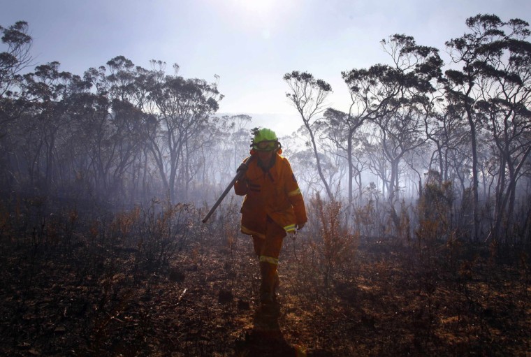 A female Rural Fire Service firefighter walks through a burnt area after trying to extinguish a small fire approaching homes near the Blue Mountains suburb of Blackheath, west of Sydney, Oct. 23, 2013.