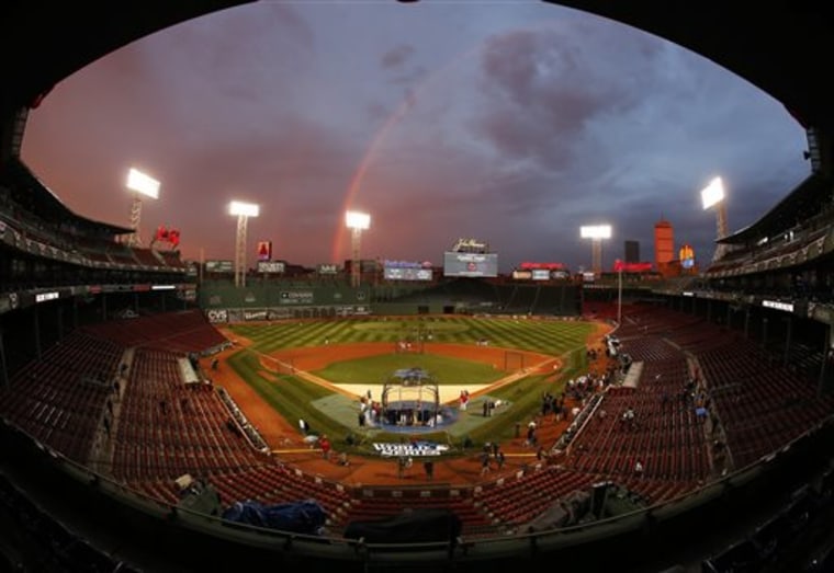 In this image taken with a fisheye lens, Boston Red Sox players take batting practice as a rainbow appears in the sky above Fenway Park Tuesday, Oct. 22, in Boston. The Red Sox are scheduled to host the St. Louis Cardinals in Game 1 of baseball's World Series on Wednesday.