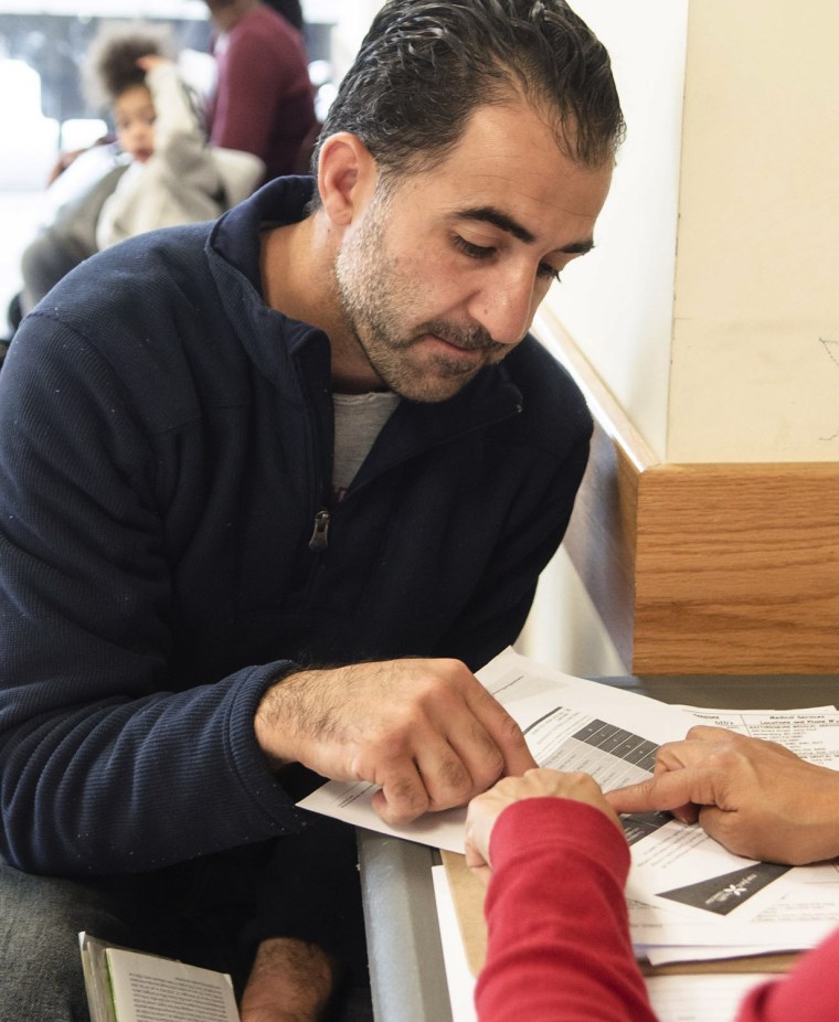 Martha Lopez of Community Clinics, Inc [R] explains to Amine Ashkar(L) of Burtonville, Md benefits that he and his family would receive under the new ...