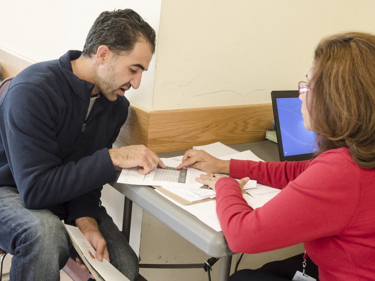 Martha Lopez of Community Clinics, Inc, right, explains to Amine Ashkar of Burtonville, Md., benefits that he and his family would receive under the n...