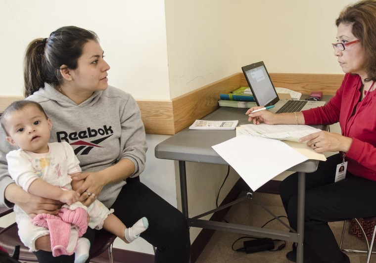 Martha Lopez of Community Clinics, Inc (R) helps Griselda Fernandez Mata(L) of Adelphi, Md fill out a paper application to receive benefits under the new Obamacare plan at the WIC(Women, Infants and Children Service) center at the Wheaton Mall in Wheaton, Md