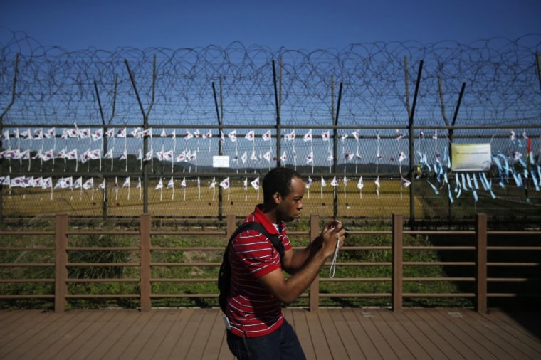 Tourist at DMZ fence in Korea takes picture.