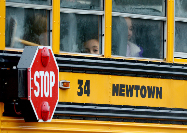 A boy looks out of a school bus as it passes preparations for the funeral of 6-year-old James Mattioli, who was killed at the Sandy Hook Elementary School shooting in Newtown, Conn., in December 2012.