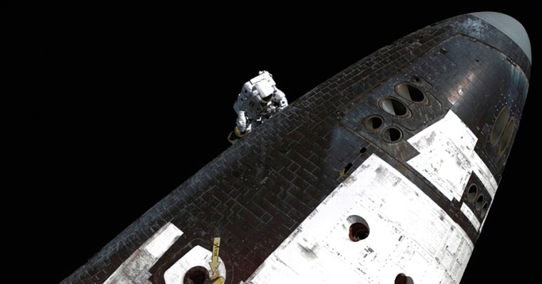 Astronaut Stephen K. Robinson inspects the shuttle Discovery's thermal protection system and removes gap fillers from its heat shield during a final spacewalk in preparation for the return to Earth in August 2005.