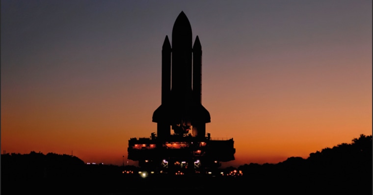 As the sun rises over Florida, a silhouetted Atlantis makes its way from the Vehicle Assembly Building to Launch Pad 39A in February 2008. The distinctive black shape stands tall and proud as it prepares for a 13-day orbital mission to deliver Europe's Columbus laboratory to the International Space Station.