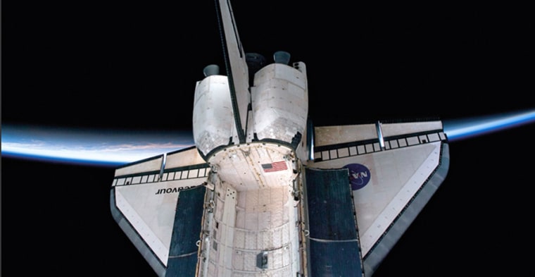 The thin auroral horizon of planet Earth provides the backdrop as Endeavour's aft section is photographed with the payload bay doors open wide in February 2010.