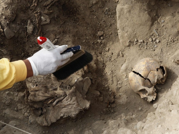 An archaeologist cleans a recently discovered tomb of an intact mummy of the Wari prehispanic culture in Lima's Huaca Pucllana ceremonial complex on O...