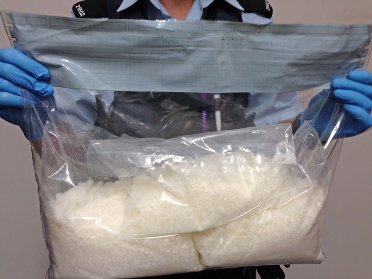 A member of the Australian Federal Police holds methamphetamine seized from an elderly couple who were allegedly conned into transporting it from Canada to Australia.