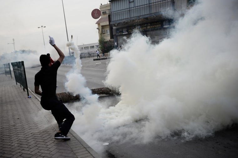 A Bahraini Shiite Muslim throws a teargas canister that had been fired by riot police during clashes following a demonstration in April in his file photo.