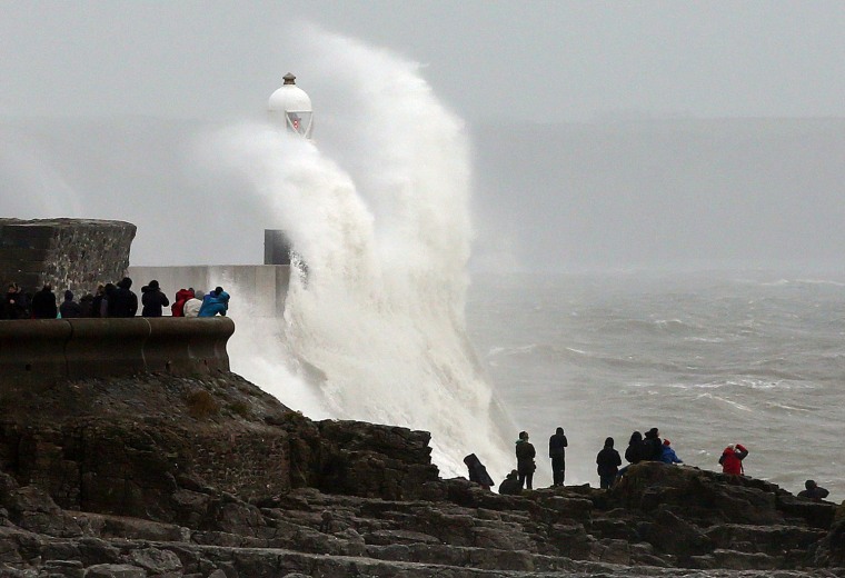 People watch as large waves break against barriers at the harbour in Porthcawl, south Wales on Oct. 27, 2013 ahead of a predicted storm.