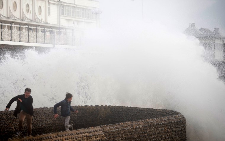 Two boys attempt to evade the spray as large waves crash against the walls of Brighton seafront, in southern England on Oct. 27, 2013.