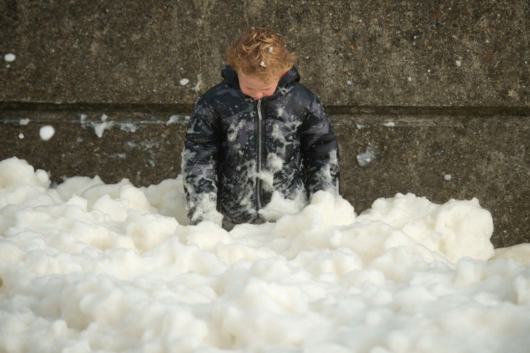 A boy plays in the foam washed ashore on the Brighton seafront on Oct.27, 2013 as high winds pick up ahead of an expected storm.