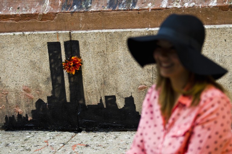 A woman poses for a picture next to new artwork by British graffiti artist Banksy of the World Trade Center towers in Lower Manhattan on Oct. 15.