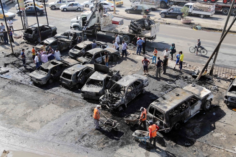 Baghdad municipality workers clear debris while citizens inspect the site of a car bomb attack in the Sha'ab neighborhood of Baghdad, Iraq, Sunday, Oct. 27, 2013.