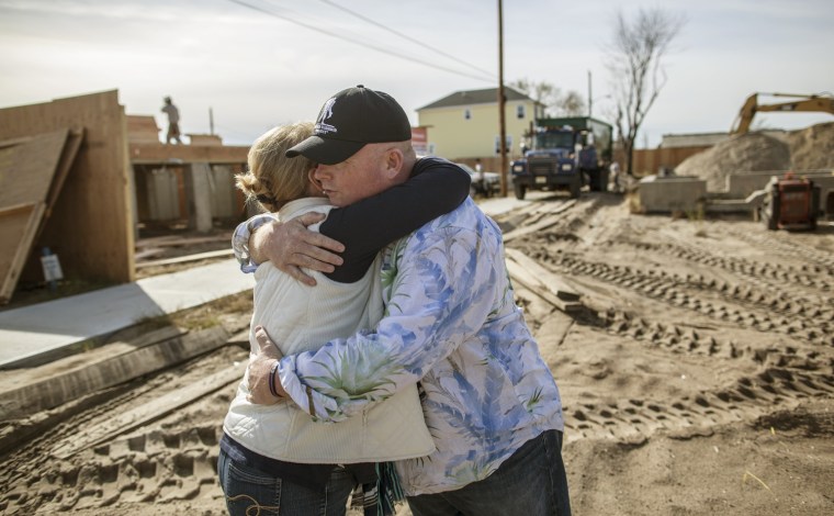 Kieran Burke of Breezy Point, whose home burned down during Superstorm Sandy, hugs his neighbor Kathy Lutz.