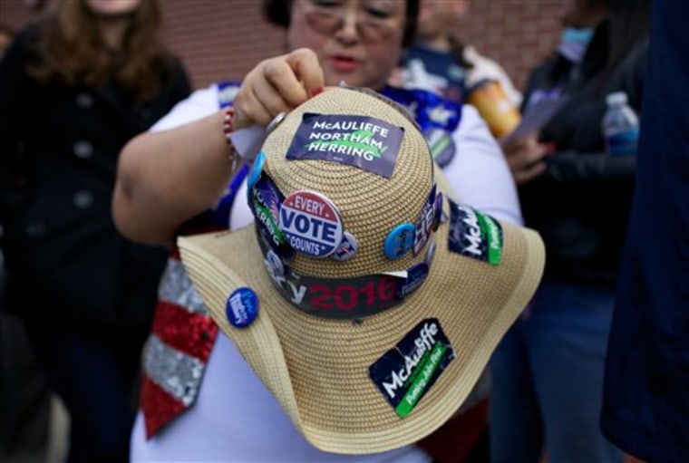 Sarah, of Alexandria, Va., who preferred not to give her last name, adds a button to her hat while waiting in line to see former President Bill Clinton and Virginia gubernatorial candidate Terry McAuliffe at an election campaign event