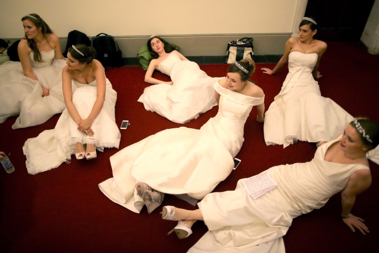 Debutantes rest their feet as they await the arrival of guests before the Queen Charlotte's Ball at the Royal Courts of Justice on Oct. 26, 2013 in London.