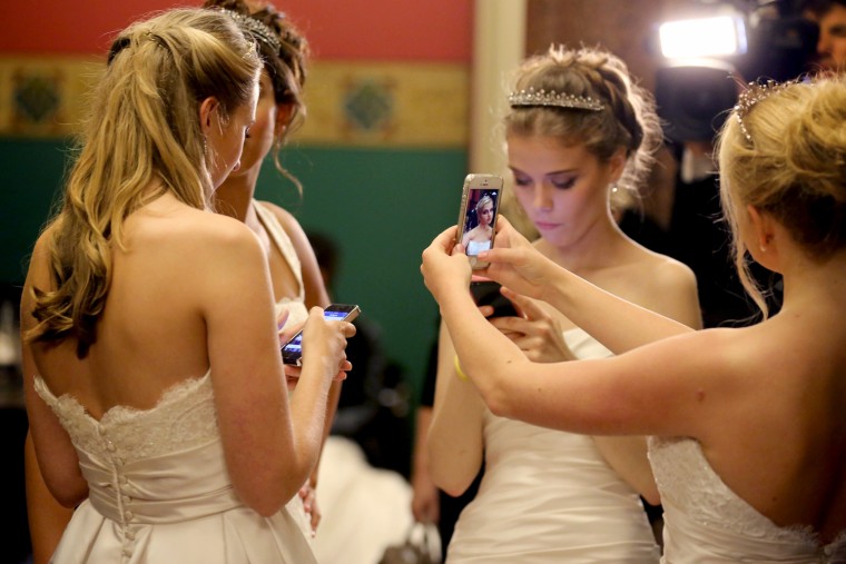 Debutantes use their smart phones to photograph themselves as they await the arrival of guests during the Queen Charlotte's Ball.
