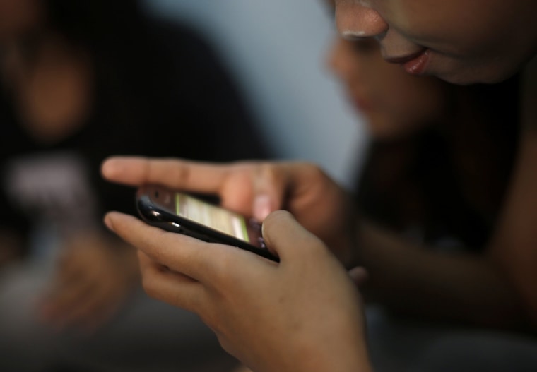 A teenage sex worker checks messages on her cellphone at a boarding house in Bandung, Indonesia.