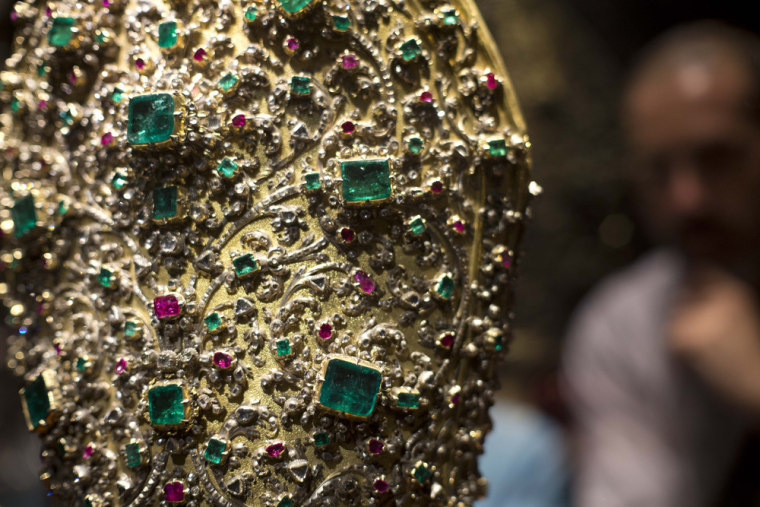 A visitor looks at the details of emeralds and diamonds amongst other precious stones on the mitre, created in 1713.