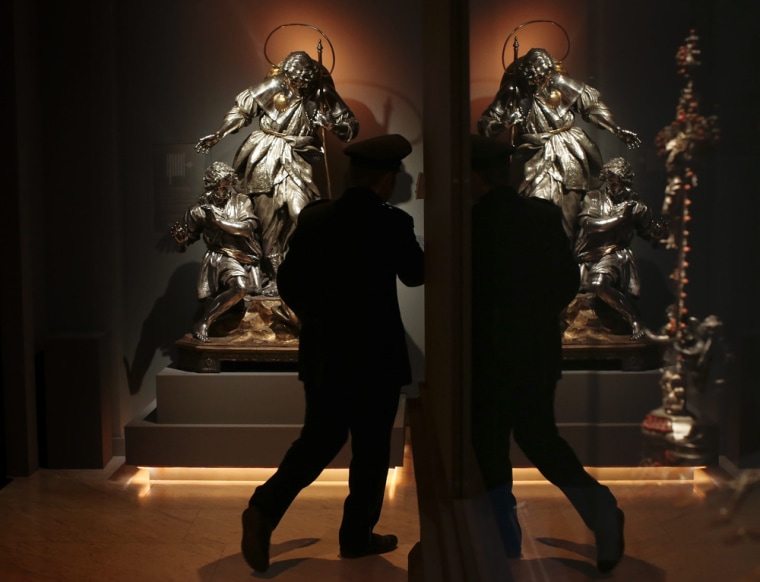 A security guard walks past a silver statue. This is the first time such a large selection of the 'Treasure of San Gennaro' has been displayed outside of Naples.