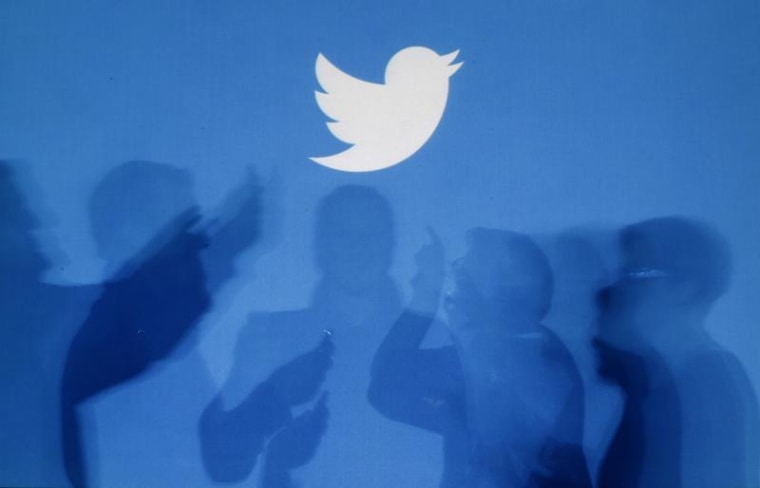 The shadows of people holding mobile phones are cast onto a backdrop projected with the Twitter logo in this illustration picture taken in Warsaw Sept...