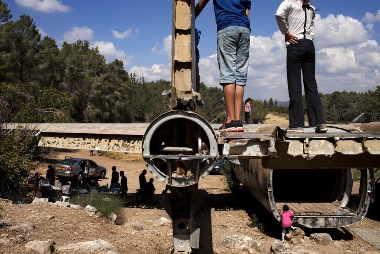 People climb on an old Nord military transport aircraft as they celebrate Israel's 65th independence day, in the Defender's Forest near Kibbutz Nahshon, central Israel, April 16, 2013. The aircraft was placed there as a monument for fallen soldiers from the parachute brigade.