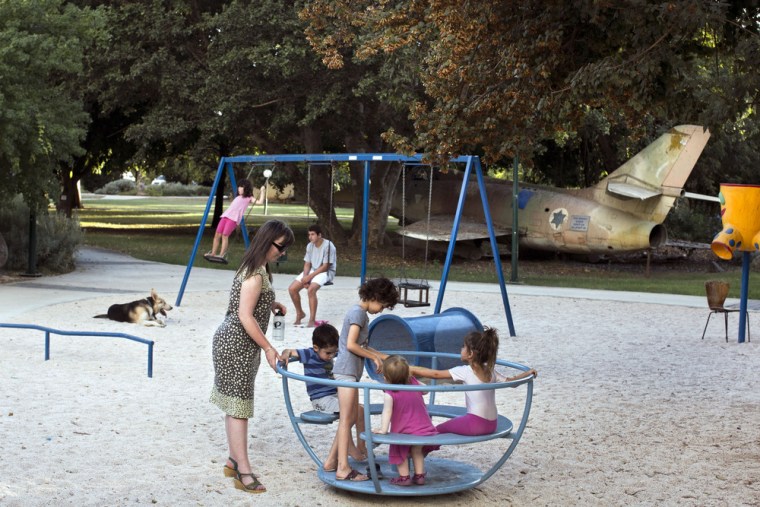 Israelis enjoy a playground where a military aircraft is placed in memory of fallen soldiers, in Kibbutz Hulata, alongside the Israeli-Syrian border, Sept. 21, 2013. Even in peacetime, the military's influence seems to be felt everywhere in Israel, with uniformed soldiers seen at bus stations and shopping malls, and war memorials peppering the country.