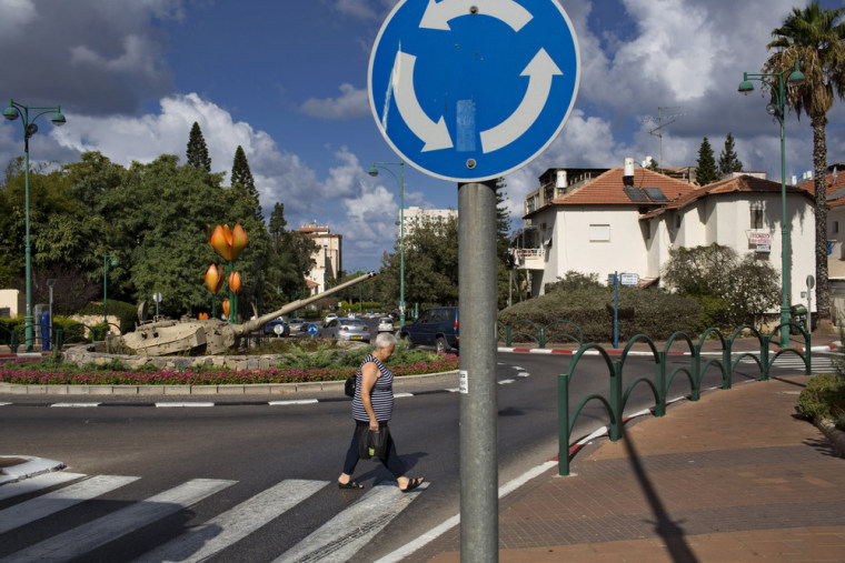 A woman crosses a road next to a tank turret placed as a memorial to Maj. Toval Gvirtzman, who was killed in the 1982 Israeli-Lebanese war, in the northern town of Hadera, Sept. 22, 2013.