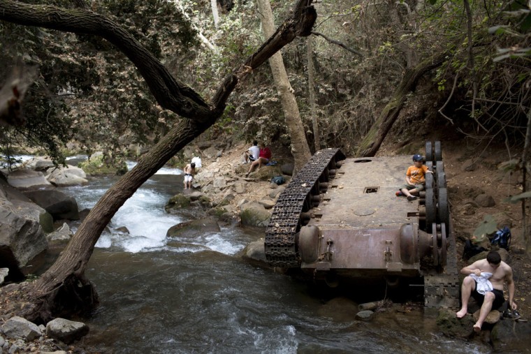 People relax beside the Banias river, where a flipped Syrian armored personnel carrier from the six-day war in 1967 still lies, Oct. 5, 2013.