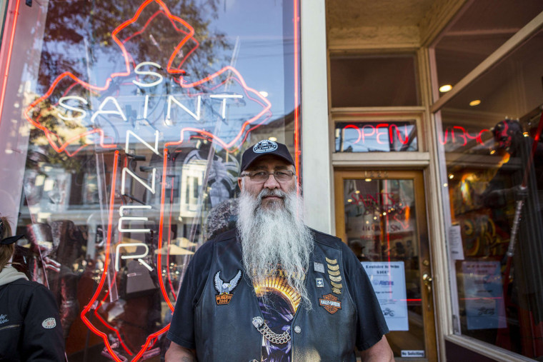 A Harley-Davidson rider stands outside the tattoo shop Saints and Sinners during the Brady Street Block Party for the 110th Anniversary Celebration in Milwaukee, Wis.