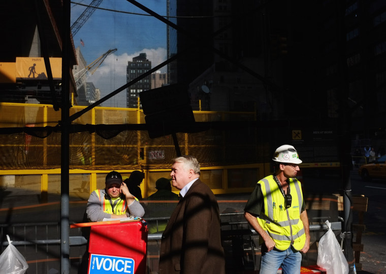 Pedestrians and workers stand by an entrance gate to the World Trade Center site in November 2011 in New York City.