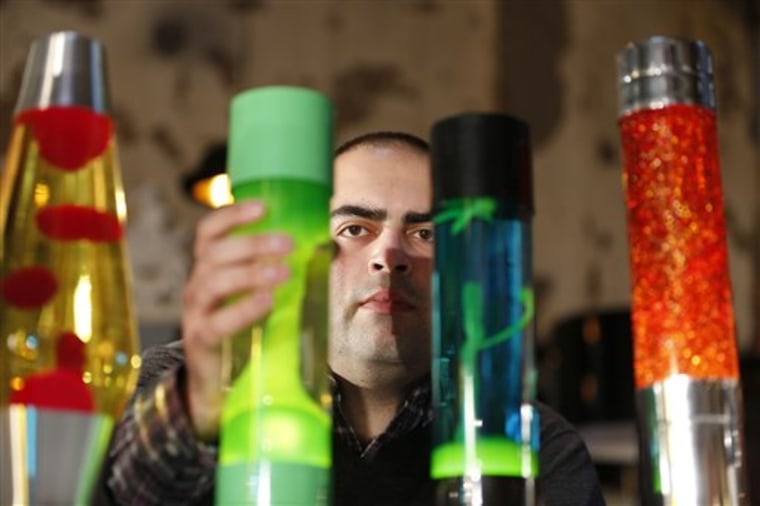 In this Monday, Aug. 19, 2013, Anthony Voss, lava lamp expert and collector, poses for the photographer in a shop in London with some of the lava lamp...