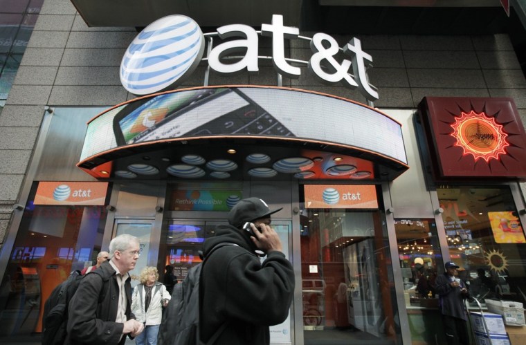 A man using a cell phone passes an AT&T store, Tuesday, Oct. 18, 2011 in New York.