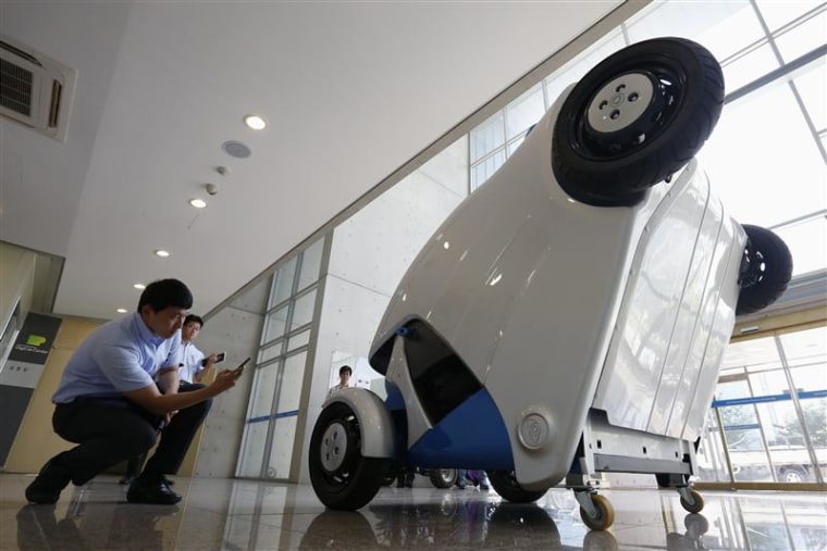 A visitor takes photographs of Armadillo-T, a foldable electric vehicle, at the Korea Advanced Institute of Science and Technology (KAIST) in Daejeon,...