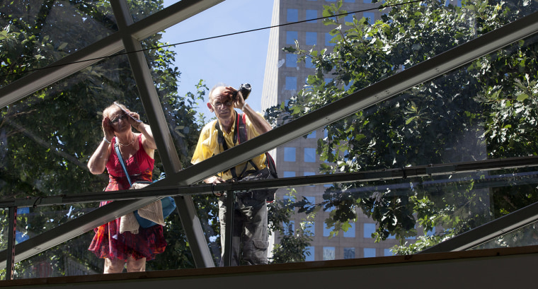 Visitors to the 9/11 Memorial peer into the atrium of the 9/11 Museum as work continues.