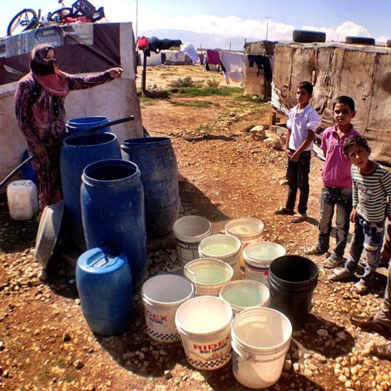 A Syrian woman pumps water from a well in a makeshift tent city. There is no clean drinking water and skin diseases like scabies have broken out in the camps.