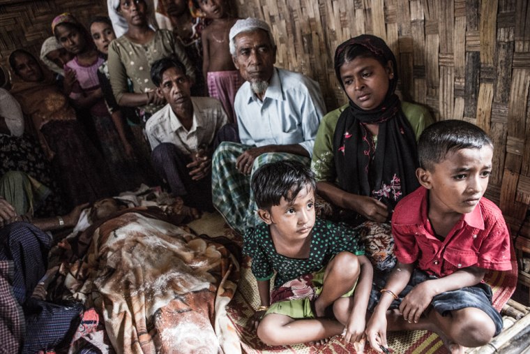 Mamuda, right, sits with her two children next to the body of her husband, Nasir, who had been fatally shot by police after clashes in an internally displaced person camp in Myanmar.