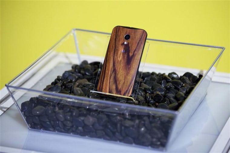 A phone with a wooden back on it rests in a display at a launch event for Motorola's new Moto X phone in New York, in this August 1, 2013, file photo....