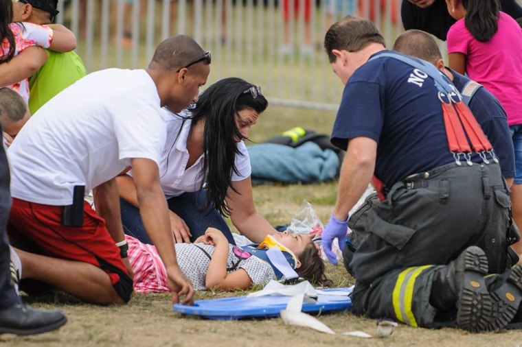 Emergency personnel treat a child after a swing ride malfunctioned Sunday and fell to the ground at the Oyster Festival in Norwalk, Conn.