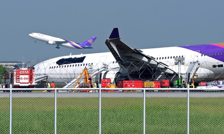 A Thai Airways plane takes off as another with its logo and name covered up rests on ground Monday after skidding off the runway at Suvarnabhumi International Airport in Bangkok.