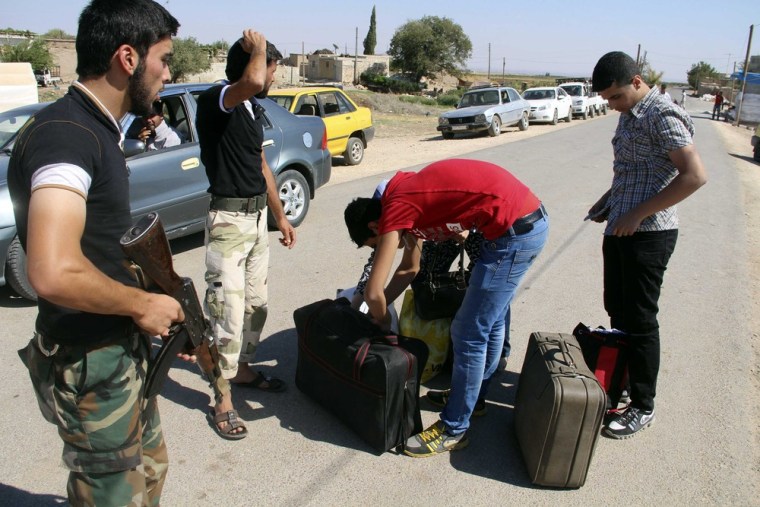 Free Syrian Army fighters search bags belonging to civilians who are attempting to enter Turkey at the Bab Al-Salam border crossing September 9, 2013.