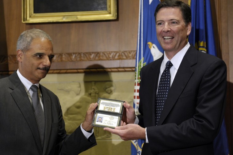 Attorney General Eric Holder, left, hands over credentials to newly sworn in FBI Director James Comey, right, at the Justice Department in Washington on Sept. 4.