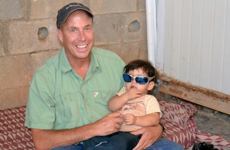 Mercy Corps aid worker Robert Maroni holds an 18-month-old child at the Zaatari refugee camp in northern Jordan.