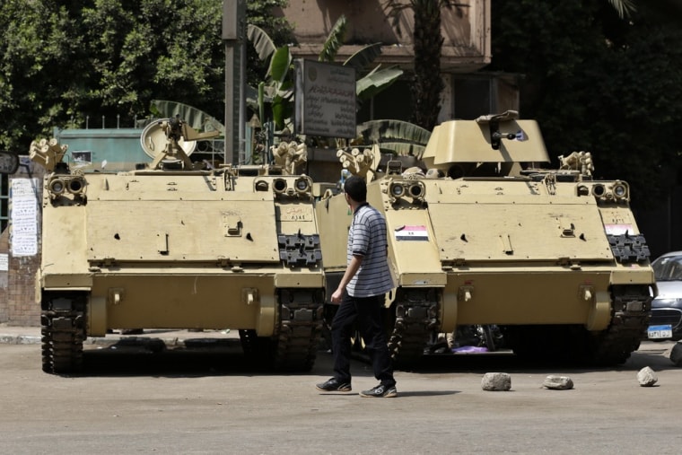 An Egyptian man walks next to armored personnel carriers on a street in Cairo on Thursday.
