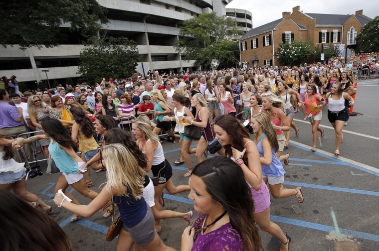 In this Aug. 17, 2013 photo, female students at the University of Alabama run from Bryant-Denny Stadium to their new sorority houses after receiving their bids in Tuscaloosa, Ala.