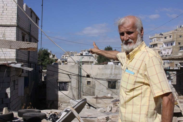 Abu Mazen Hamza, age 67, on his rooftop, points toward the street where he saw 12 dead bodies while fleeing from gunmen during the Sabra-Shatila massacre in 1982.